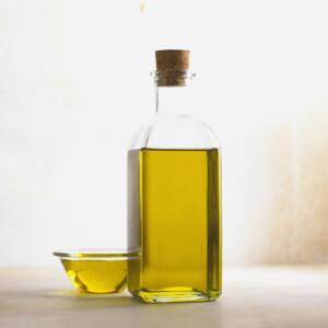 Botella de aceite de oliva junto a un pequeño recipiente, también de aceite de oliva